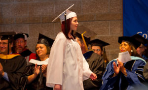 Photo of Artesia Cyrus walks up on stage to recieve her GED certificate from President Carrie Hauser, at CMC Rifle.