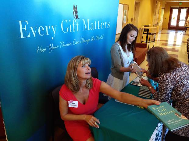 Photo of Carrie Morgridge signing her book "Every Gift Matters"