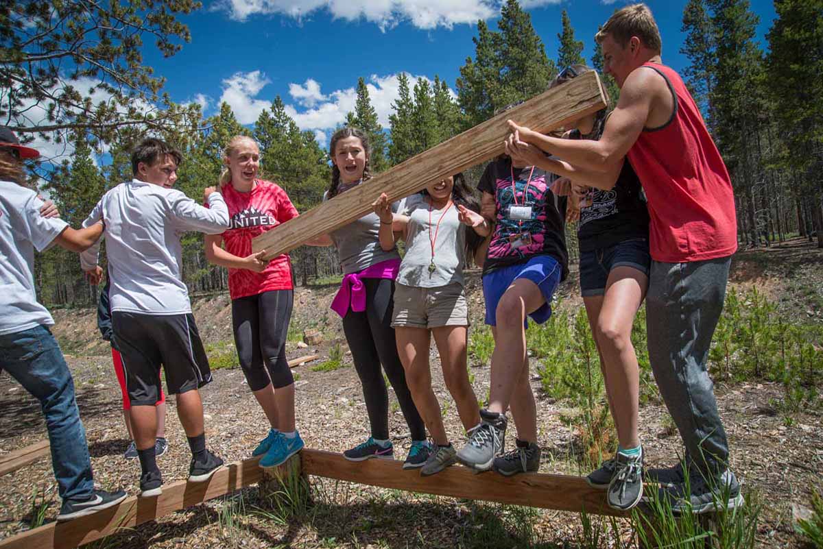 photo: At a 2016 First Ascent team-building exercise at Colorado Mountain College Leadville’s ropes course, students balance on two-by-fours.