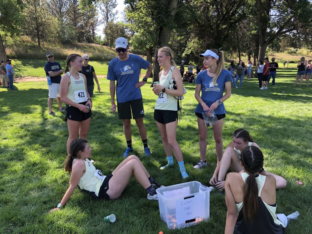 The CMC women’s cross-country team talks with Head Coach Darren Brungardt after crossing the finish line at the Ted Castaneda Cross-Country Classic in Colorado Springs on Sept. 11, 2021.